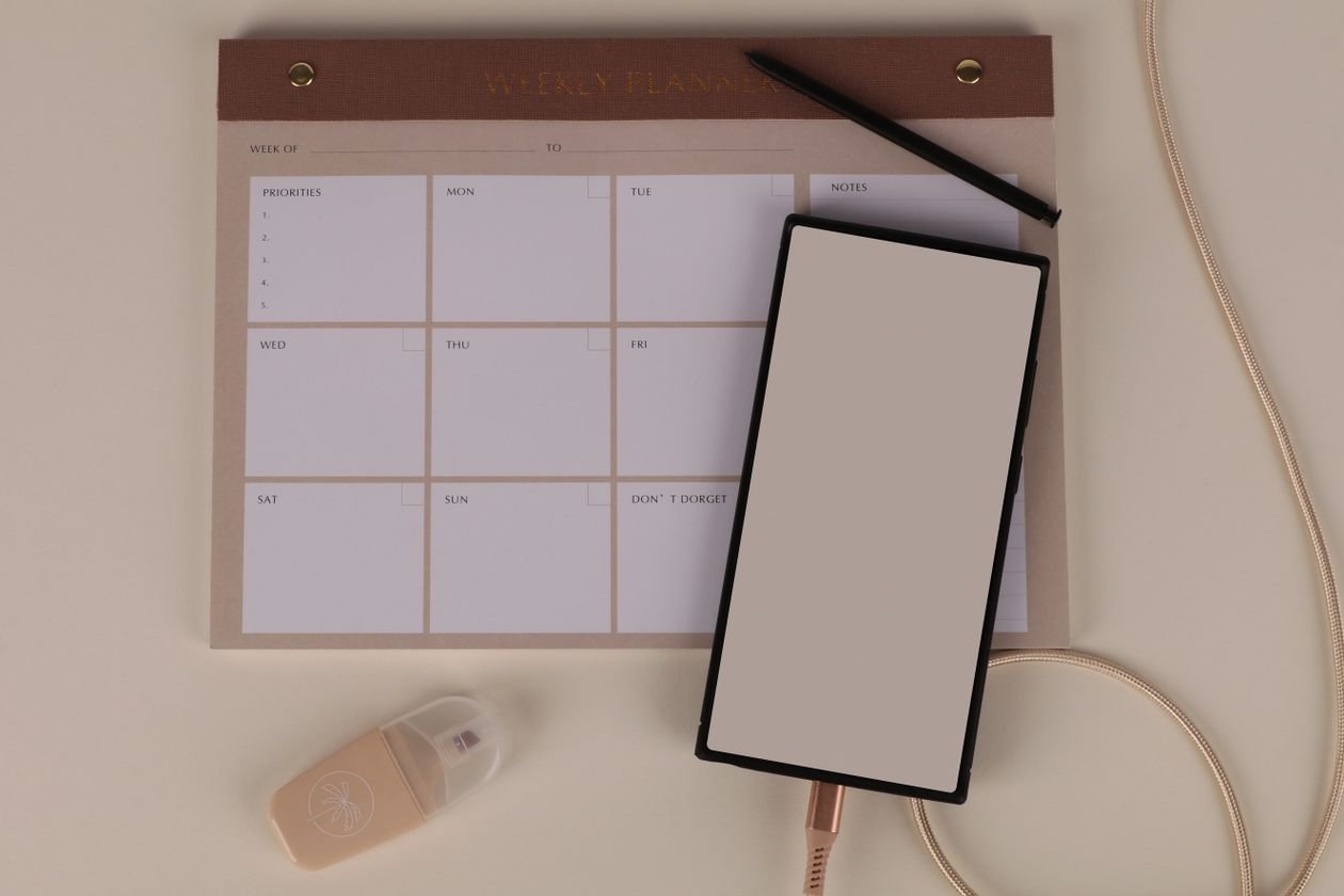 Flat lay of a weekly planner, smartphone and stationery used to plan an Instagram posting schedule
