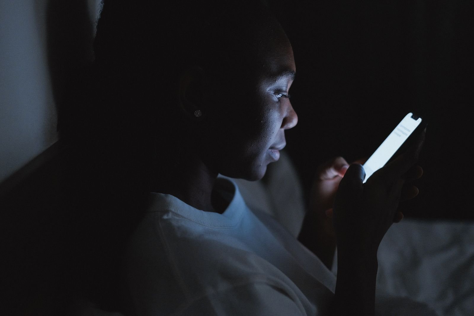 Woman checking her Instagram Story viewers on a phone in a dark room